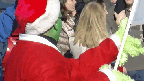 a man dressed as santa claus is standing in front of a crowd of people