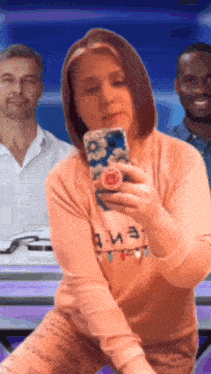 a woman is taking a selfie in front of a man and another man