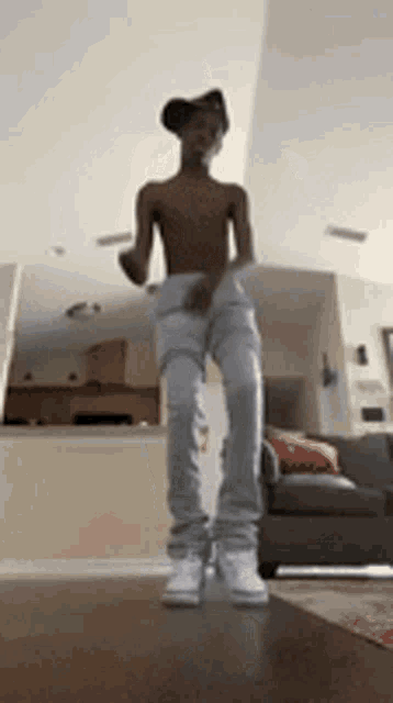 a young man without a shirt is dancing in a living room .
