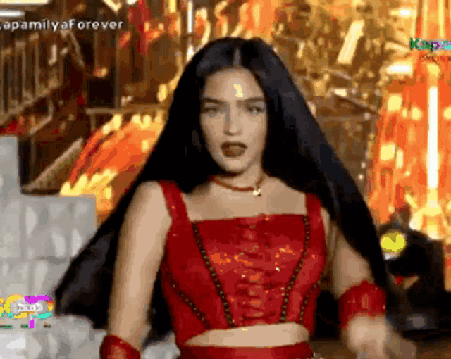 a woman with long black hair is wearing a red crop top .