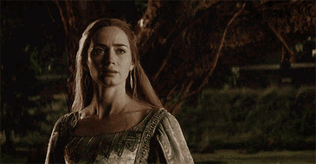 a woman in a green dress is standing under a tree