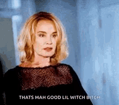 a woman in a black dress is standing in a hallway and talking to someone .