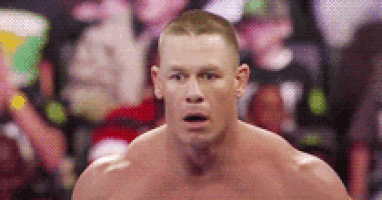 a shirtless wrestler is standing in front of a crowd and making a surprised face .