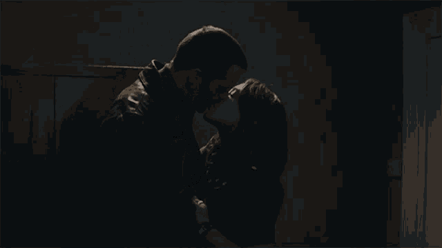 a man and a woman are kissing in the dark