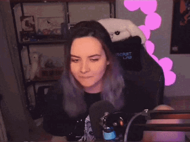 a woman with purple hair is sitting in a chair with a microphone in front of her