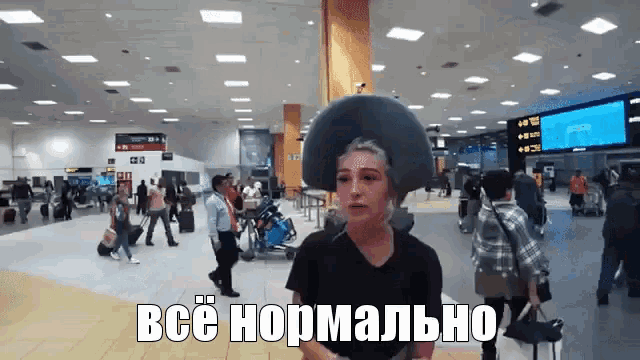 a woman wearing a cowboy hat stands in a crowded airport with the words " все нормально " on the bottom