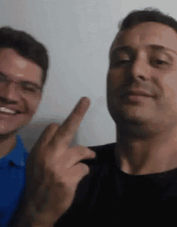 two men are posing for a picture and one of them is pointing at the camera