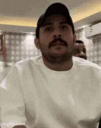 a man with a mustache wearing a hat and a white shirt