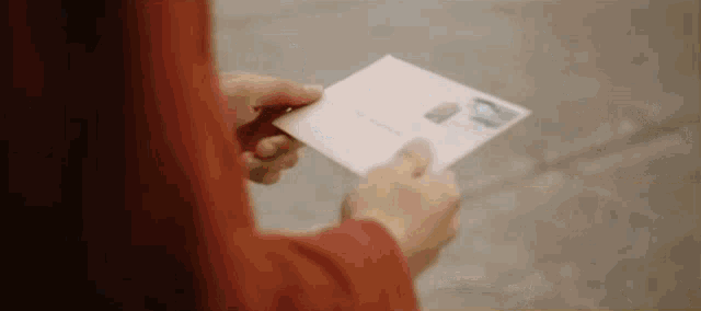 a person is holding an envelope with a stamp on it in their hands .