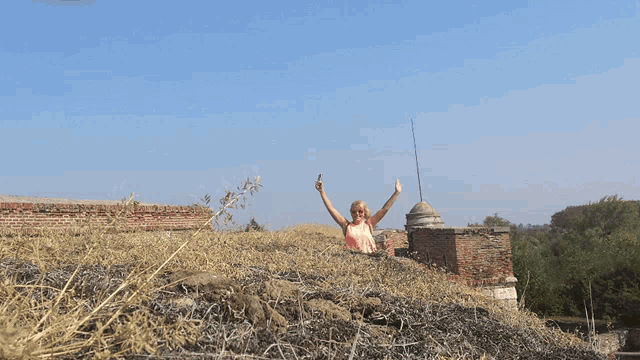 a woman sitting on top of a pile of dry grass