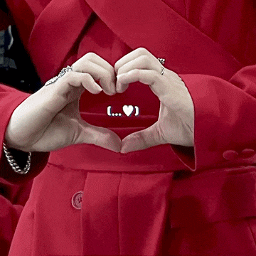 a woman in a red coat makes a heart with her hands