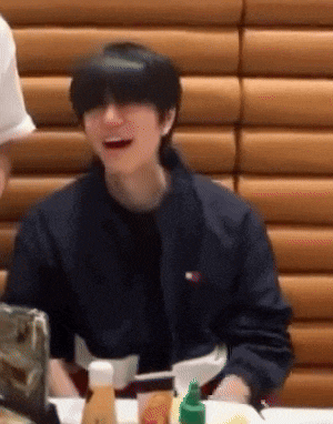 a man wearing a tommy hilfiger jacket is smiling while sitting at a table