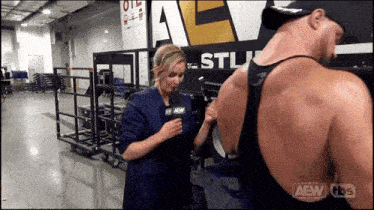a woman is talking into a microphone in front of a sign that says aew on it
