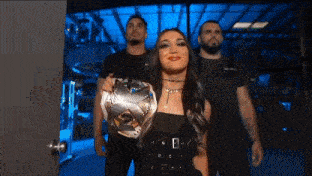 a woman in a black dress is holding a silver wrestling championship belt