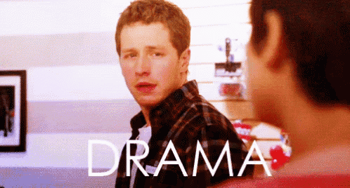 a man in a plaid shirt is standing next to another man with the word drama written in white letters
