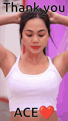a woman in a white tank top is holding her hair with her hands .