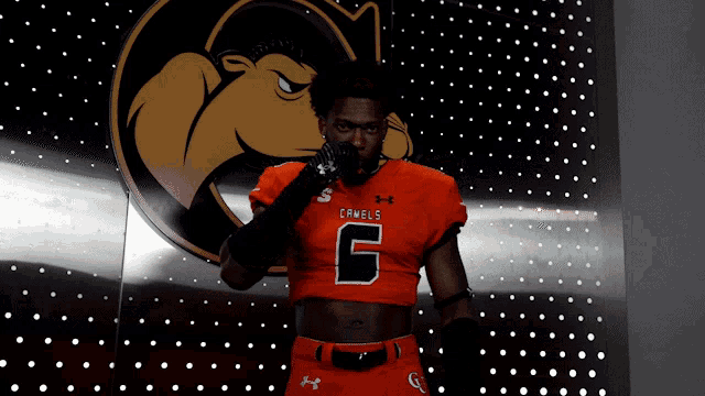 a man in a camels jersey stands in front of a wall of dots