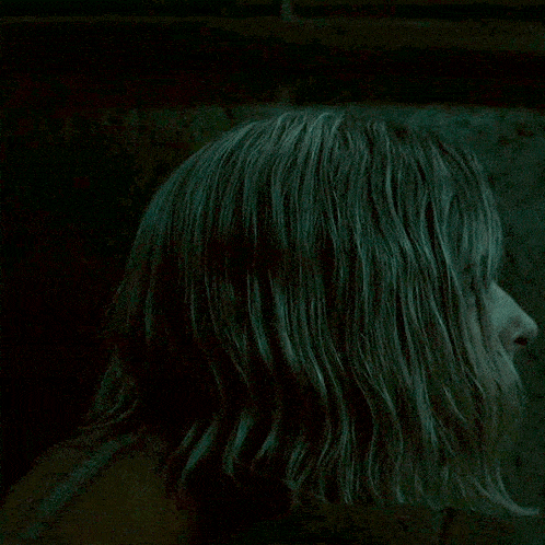 a woman with blonde hair is looking at the camera in a dark room