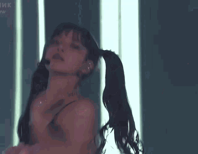 a woman in a black bra and pink skirt is dancing in a dark room .