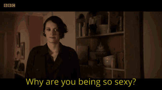 a woman is smiling in front of a bookshelf and the words why are you being so sexy