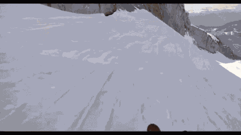 a person is skiing down a snow covered mountain with a large rock in the background .