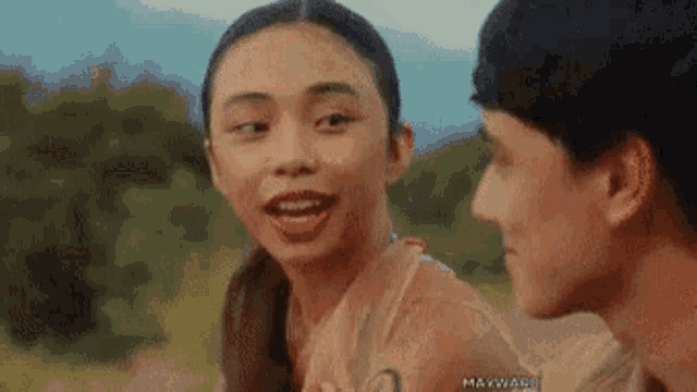 a man and a woman are standing next to each other in a field and the woman is smiling .