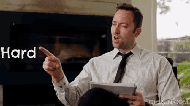 a man in a white shirt and tie is pointing to the word hard