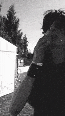a black and white photo of a man smoking a cigarette in front of a white tent