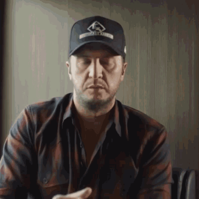 a man wearing a plaid shirt and a hat with a logo that says ' ford ' on it
