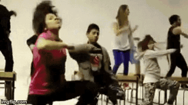 a group of children are dancing in a classroom while sitting on chairs .
