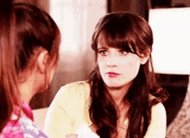 two women are sitting next to each other talking to each other .