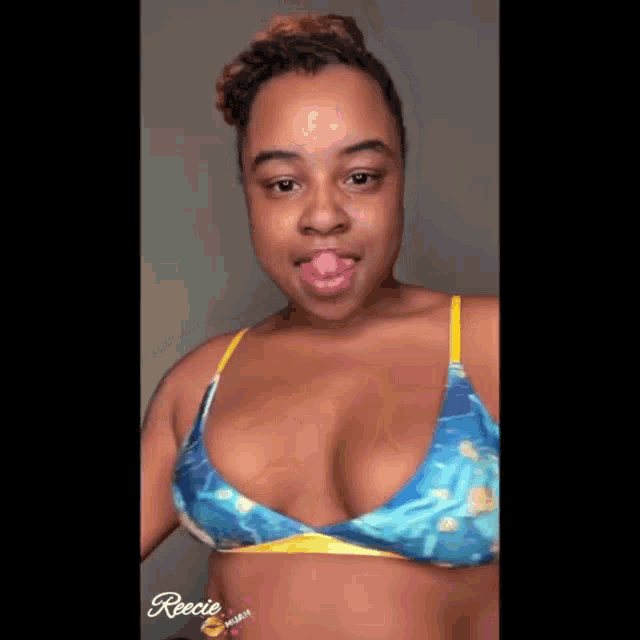a woman in a blue and yellow bikini top is licking her lips .