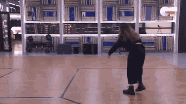 a woman is dancing on a wooden floor in a gym .