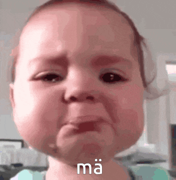 a baby is crying and making a funny face with the word ma written on it .