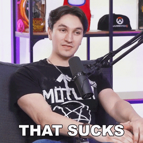 a man sitting in front of a microphone with the words that sucks on his arm