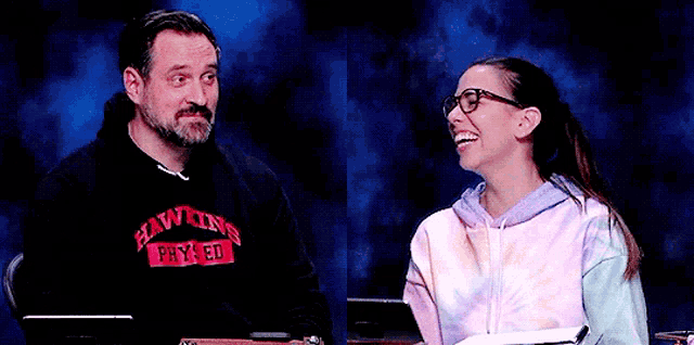 a man wearing a hawkins shirt is talking to a woman