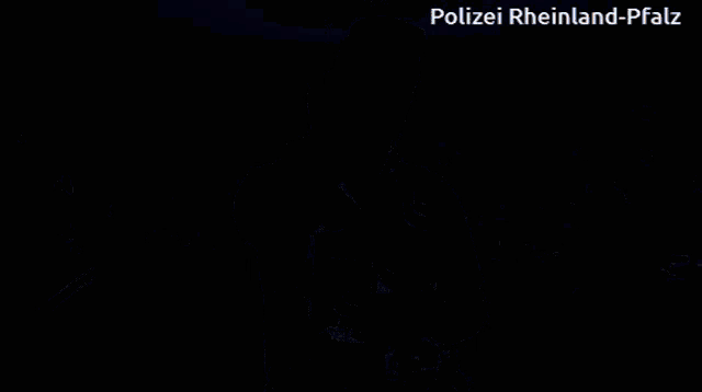 a man in a polizei vest stands in front of blue lights