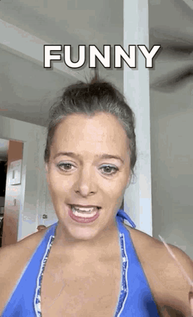 a woman in a blue bikini top is making a funny face while standing in a room .