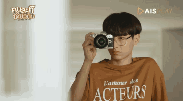 a young man wearing a t-shirt that says l' amour des acteurs holds a camera