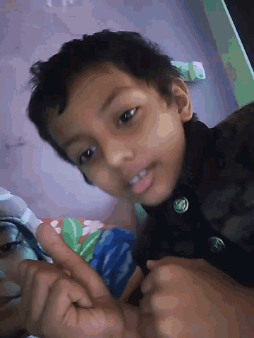 a young boy wearing a black jacket with a green button on the front