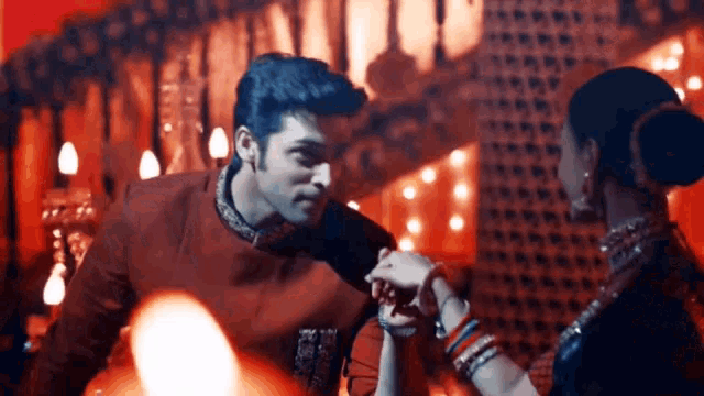 a man and woman are holding hands in a room with red lights