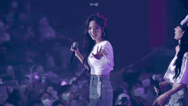 a woman in a white shirt is holding a microphone in front of a crowd