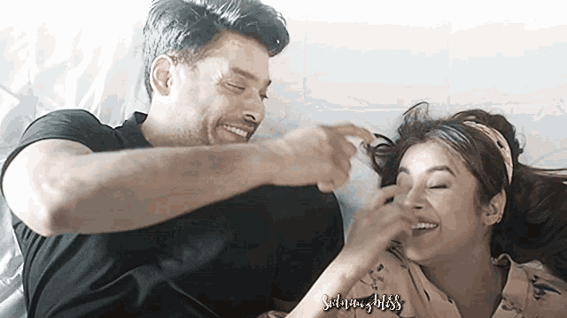 a man and a woman are laying on a bed and the woman is touching the man 's hair .