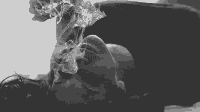 a woman is laying down with smoke coming out of her mouth .