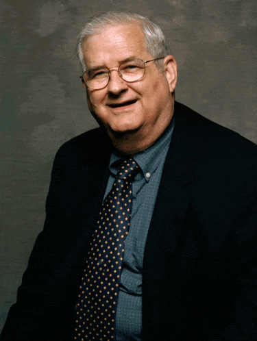 an older man wearing glasses and a suit is smiling for the camera