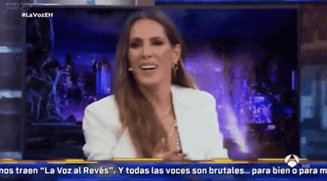 a woman in a white jacket is laughing on a television screen