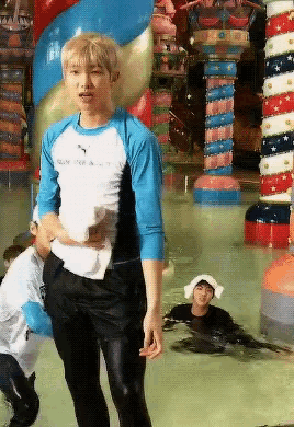 a man in a blue puma shirt stands in a water park