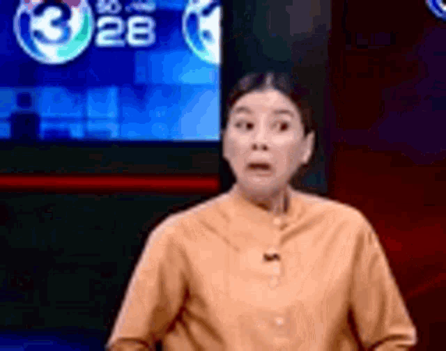 a woman is sitting in front of a television screen and making a surprised face .