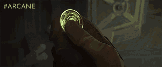 a person is holding a coin that is glowing in the dark and says #arcane on the bottom