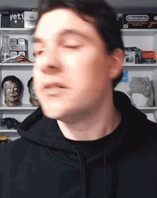 a man in a black hoodie stands in front of a nintendo game